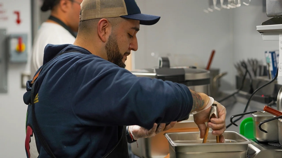 Jesus "Sal" Ramirez, food truck coordinator for AggieEats serves food in the kitchen of the food truck.